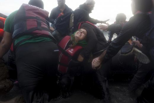 Syrian refugee struggles to get off an overcrowded dinghy as refugees and migrants arrive in rough sea on the Greek island of Lesbos, after crossing a part of the Aegean Sea from the Turkish coast